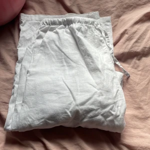 Vita linnebyxor - Säljer ett par vita linnebyxor som är perfekta för sommaren. De har en bekväm elastisk midja med snörning för justerbar passform. Byxorna är lösa och luftiga, vilket gör dem idealiska för varma dagar. Perfekta för en avslappnad stil!