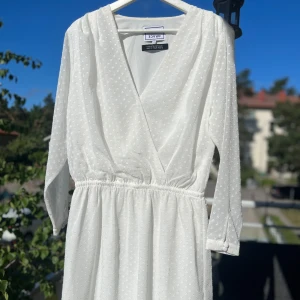 Vit klänning 🤍✨ - Säljer en superfin vit klänning med små prickar över hela tyget. Den har en omlott-design framtill och långa ärmar.  Klänningen är i nyskick och har en elastisk midja. Stl 38. Hämtas på Hägerstensåsen eller ök 🤍✨