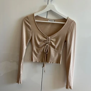 Beige topp från nakd - Beige topp från nakd, lite croppad Knytdetalj vid bröstet och fina sömmar på ärmar. 
