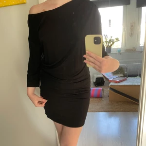 Svart klänning från Pernilla Wahlgren - Säljer en elegant svart klänning från Pernilla Wahlgren. Den har en stilren offshoulder-design och trekvartsärmar. Perfekt för en festlig kväll eller en utekväll med vänner. Klänningen är i nyskick och har en tight passform som framhäver figuren.