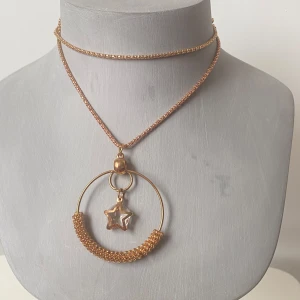 Guldigt halsband med stjärndetalj - Säljer ett supercoolt guldigt halsband med en unik design. Halsbandet har en tunn kedja och ett stort cirkelformat hänge med en stjärna i mitten. Perfekt för att ge din outfit en extra touch av glamour! ✨
