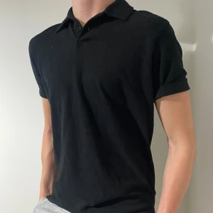 Svart pikétröja - Snygg och stilren svart pikétröja med klassisk krage och korta ärmar. Perfekt för både vardag och fest. Passar bra till jeans eller chinos för en avslappnad look.