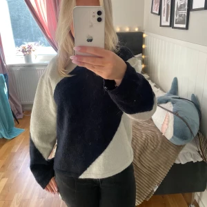 Svart och blå tröja - Säljer en stilren blå och vit tröja med långärmad design. Tröjan har ett unikt diagonalt mönster som ger en modern touch.