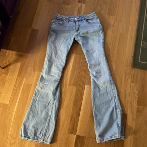 Ljusblå bootcut jeans - Säljer ett par snygga ljusblå bootcut jeans, de är lågmidjade med broderi på fickorna. De har en fläck på baksidan (se bild)