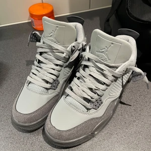 Jordan 4 wet cement  - Snygga grå Nike Air Jordans med klassisk design och Jumpman-logga på plösen. Skorna har en stilren look med grå snörning och detaljer i olika grå nyanser. Perfekta för den som vill ha en stilren och sportig stil. Ej nya som i bilden 