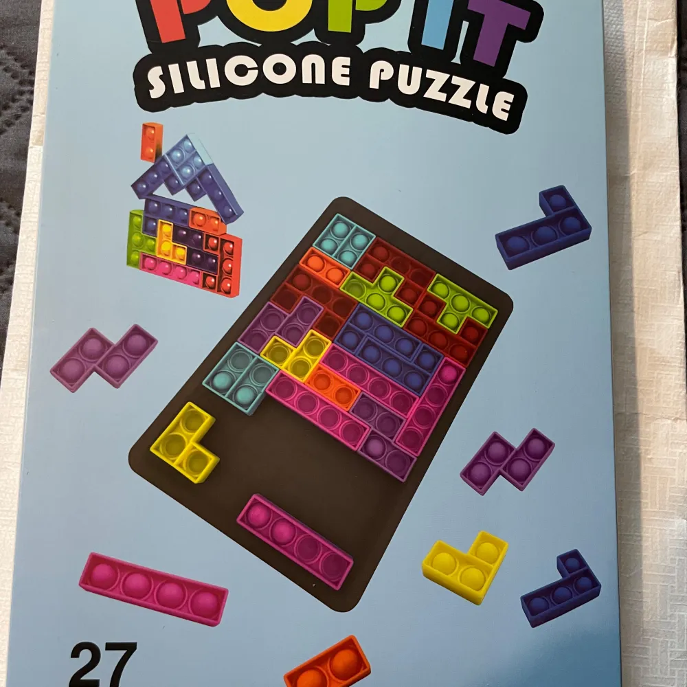 Pop It Silicone Puzzle är ett färgglatt pussel med 27 bitar i olika former och färger. Pusslet är tillverkat av silikon och har en Tetris-liknande design. Perfekt för barn från 3 år och uppåt, det erbjuder både underhållning och utveckling av finmotorik.. Böcker.