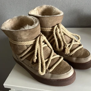 Beige skor  från Inuikii med snörning - Säljer ett par beige skor från Inuikii med grov snörning och högt skaft. Skorna har mjukt och varmt foder inuti samt detaljer i mocka och skinn. Perfekta för kalla dagar och har en platt sula. jag har 38 egentligen men dom passade perfekt