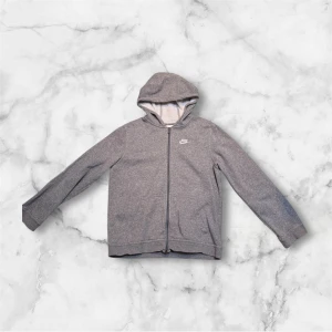 Grå Nike hoodie - Säljer min fina Nike hoodie då den inte kommer till användning eftersom den inte passar mig längre. Tröjan är i bra skick, har inga fläckar eller är sönder. Den är använd några gånger. Om ni undrar något så kan ni skriva till mig.