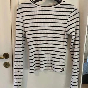 Vit och svart randig långärmad topp från H&M - Säljer en vit och svart randig långärmad topp från H&M Divided. Toppen är ribbad och har en klassisk rund halsringning. Perfekt för en stilren och avslappnad look. 🖤🤍