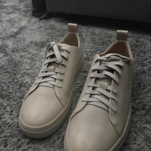 Beige/olive green sneakers från Tiger of Sweden - Snygga beige sneakers från Tiger of Sweden i skinn med snörning. Perfekta för en stilren look. Storlek 41.