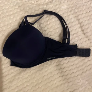 Mörkblå bh från Calvin Klein - Snygg mörkblå bh från Calvin Klein med vadderade kupor och justerbara axelband. Perfekt för en stilren look . Enkel design med diskret logga på sidan. Använd enbart en gång, legat i en låda därav lite dammig 😅storlek 70 DD/ 70 E-F. Köpt för 550 och pris kan diskuteras vid snabb affär 