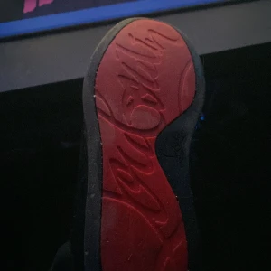 Christian loubioutin skor - Snygga svarta sneakers från Christian Louboutin med den ikoniska röda sulan. Skorna har nitar på ovansidan och snörning. Perfekta för att ge en edgy touch till din stil.