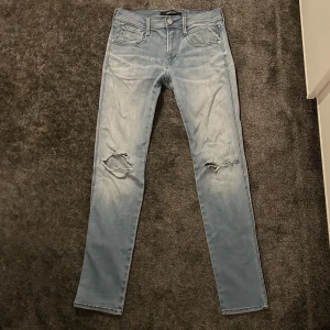 Replay Jeans - Säljer ett par ljusa jeans från Replay med slitna detaljer på benen. Skicket är som nytt, storlek W28 L32! Vid några funderingar är det bara att kontakt.
