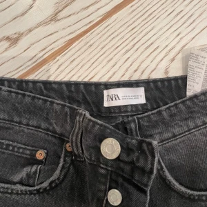 Svarta jeans från Zara - Snygga svarta jeans från Zara med knappstängning och klassisk femficksdesign. Perfekta för en stilren look. Jeansen är straight fit är använda 2 gånger och i mycket bra skick 
