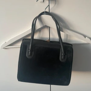Svart vintage handväska  - Elegant svart handväska. Perfekt för att hålla dina saker säkra och organiserade. Stilren design som passar till många tillfällen.