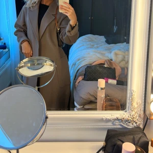 Beige kappa - Säljer en stilren beige kappa med klassisk design. Den har långa ärmar och en elegant passform som passar perfekt för kyligare dagar. Kappan är utan synliga detaljer som knappar eller dragkedja, vilket ger den ett minimalistiskt utseende.