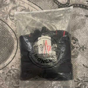 Svart dunjacka från Moncler. Tar emot byten mot moncler jackor och cardigan - Säljer en snygg svart dunjacka från Moncler med dragkedja och ribbade detaljer. Jackan har Moncler-logotypen på bröstet och är fylld med 90% gåsdun för extra värme. Perfekt för kyliga dagar!