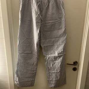 Randiga byxor med snörning - Säljer ett par randiga byxor från 157 i storlek M. Byxorna har en bekväm passform med snörning i midjan och är perfekta för en avslappnad stil. De är blå och vita med ett klassiskt randigt mönster.