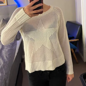 Vit stickad tröja med stjärna - Säljer en vit stickad tröja med ett stort stjärnmönster på framsidan. Tröjan har långa ärmar och en rund halsringning. Perfekt för en avslappnad stil.