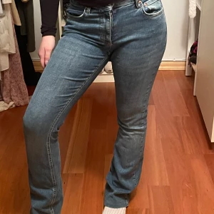Blå jeans med bootcut - Snygga blå jeans med bootcut-stil och klassisk femficksdesign. De har en normal passform och är perfekta för en avslappnad look. Jeansen har en dragkedja och knapp framtill. Jeansen har storlek 36. 