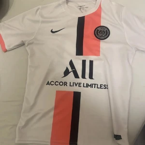 PSG 21/22 borta kit MESSI - Klass fotbollströja med både PSG och Messi. Denna tröja var Messis första säsong i PSG, vilket innebar historia. Tröjan är stilren och perfekt som vardagligt bärande eller för samling. Passar alla Messi, PSG, Frankrike och Ligue 1 fans. Tröjan är tyvärr icke äkta men smälter in som bara den! Skriv om fler frågor!