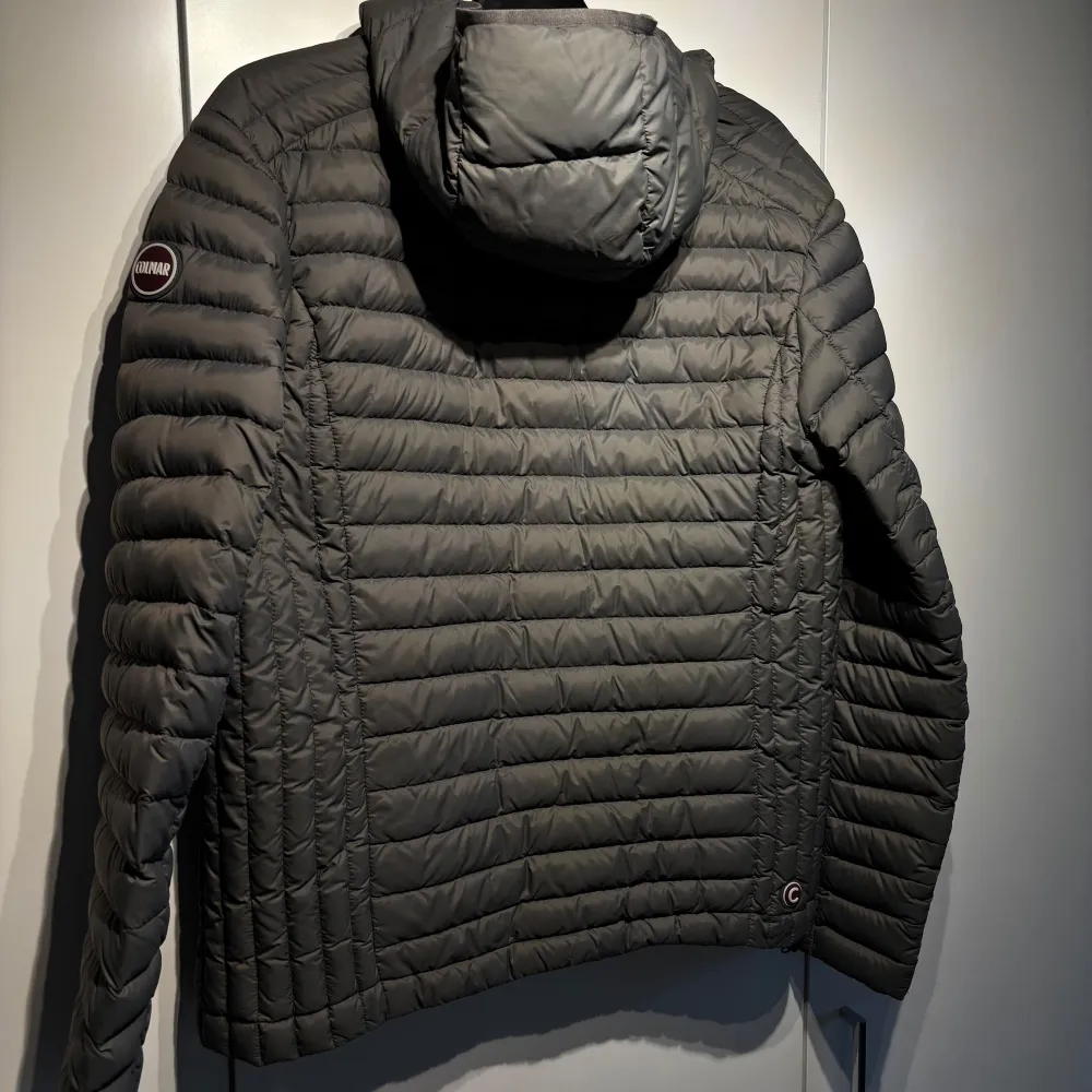 Säljer en stilren grå pufferjacka från Colmar. Jackan har en quiltad design med dragkedja framtill och långa ärmar. Perfekt för kyligare dagar med sin lätta och bekväma passform.. Takit.