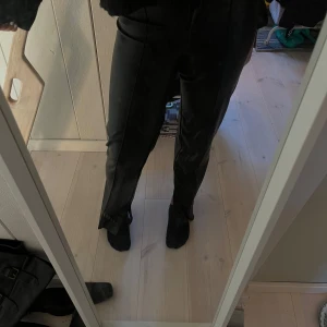 Svarta Skinnbyxor med slits - Säljer nu dessa svarta skinnbyxor (inte äkta skinn) som är köpta på new Yorker för några månader sedan. De är sanna i storleken (34) och även bra i längden på mig , jag är 170cm lång. ❤️ skriv för mer info🥰