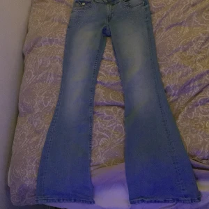 Blå jeans, Low waist, utsvängda ben från H&M - Snygga blå jeans från H&M med utsvängda ben och låg midja. De har justerbar midja och är dekorerade med små glittriga detaljer vid fickorna. Perfekta för en trendig look. Det är bara fjärilen på back fickan som ha tappat diamanter/glitter.