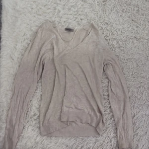 Beige långärmad tröja  - Säljer en stilren beige tröja med v-ringning. Tröjan har långa ärmar och är perfekt för en avslappnad look. Passar bra till både jeans och kjol. Perfekt för höst och vår!