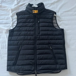 Svart dunväst från Parajumpers - Säljer en snygg svart dunväst från Parajumpers i super fint skick helt utan skador och defekter. Perfekt för kyligare dagar med sin quiltade design och stilrena look. Den är i storlek M. Hör gärna av er vid frågor