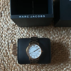 Guldfärgad klocka från Marc Jacobs - Klocka från Marc Jacobs i guld med vit urtavla. Sparsamt använd, inga täcken på användning. Allt i originalförpackning. Ordinarie pris 2 600kr