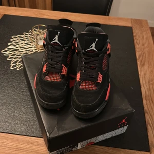 Svarta och röda Nike Air Jordans - Säljer ett par snygga svarta och röda Nike Air Jordans. Skorna har en klassisk design med snörning och den ikoniska Jumpman-loggan. Perfekta för dig som vill ha en stilren och sportig look. Den här ai plick grejen skrev åt mig fett nice men ja ungefär samma lite använda tror inte man ser på bilden säljer billigt för ska flytta o behöver göra mig av med saker o ting. 44-45 mebn passar 43