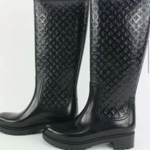 Svarta stövlar med monogram louis vuitton rain boots - Snygga svarta stövlar från Louis Vuitton med det ikoniska monogrammönstret. Stövlarna har en robust sula och är perfekta för en stilren look. De är tillverkade i ett glänsande material som ger en lyxig känsla. Storlek 37 men passar även 36 