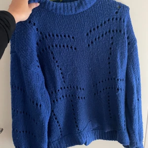 Blå stickad tröja från Gina Tricot - Säljer en superfin blå stickad tröja från Gina Tricot. Den har ett snyggt hålmönster som ger en cool look. Perfekt för höst och vinter, och den är riktigt mysig att ha på sig. Tröjan har långa ärmar och en ribbad krage.