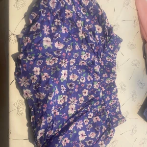 Blommig kjol  - Snygga kjol med blommigt mönster i blått, rosa och vitt. Kjolen har en elastisk midja och är i en lätt och luftig kvalitet.