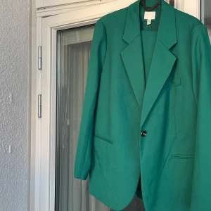 Grön kostym - Grön kostym från H&M i stl L. Endast använt 1 gång. Färger är något mörkare än bilden tagen i dagsljus. Skulle säga att det är en typiskt mörkgrön kostym med lite oversized kavaj.