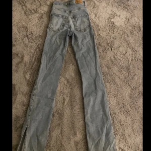 Blåa högmidjade jeans med slits - Varan är mycket andvänd men inga hål  eller så, lite slitna längst ner men inget man tänker på när man har dem på sig.
