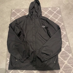 the north face regnjacka - Säljer denna regnjacka då jag ej använder den. Spännena nere vid midjan är borta.OBS! Säljer för de billiga priset då jag inte tror den är äkta!