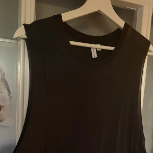 Svart ärmlös topp - Säljer en stilren svart ärmlös klänning. Perfekt för både vardag och fest. Klänningen har en enkel design och är gjord i ett mjukt material som känns skönt mot huden.