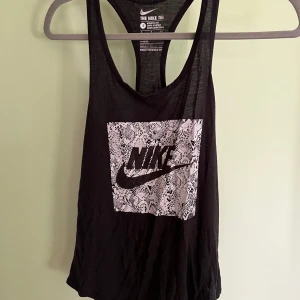 Svart träningslinne, Nike - Material: 50% polyester, 25% bomull, 25% viskos   Säljer ett lila och ett svart i samma modell. 