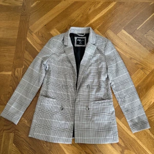 Rutig kavaj från FB Sister - Säljer en snygg rutig kavaj från FB Sister i storlek M. Den har en klassisk design med dubbelknäppning och långa ärmar. Perfekt för både höst och vår, och funkar lika bra till vardags som till fest. Kavajen är i fint skick men lite nopprig. 