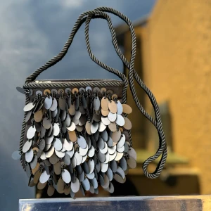 Glittrig axelväska med paljetter - Liten svart axelväska med massor av glittriga paljetter som ger en festlig look. Väskan har en flätad axelrem. Mått -se linjal på bild. Hämtas på Hägerstensåsen eller ök 🖤