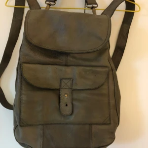 Ryggsäck i skinn - Välbevarad ryggsäck från Gudrun Sjödén i mjukaste grönt skinn. Handtag, många fack, fint foder och tryckknappar för extra bra stängning. 