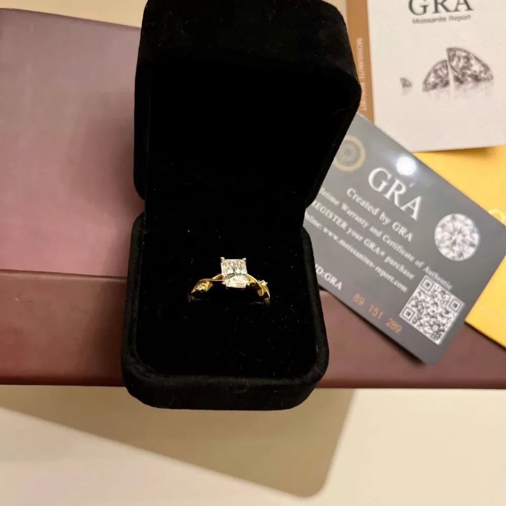 Säljer en elegant guldfärgad ring med en stor, fyrkantig sten i mitten. Ringen kommer i en snygg svart ask och har ett certifikat från GRA. Perfekt för speciella tillfällen eller som en lyxig present!  Size 54 . Accessoarer.