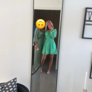 Grön klänning med volangdetaljer - Säljer en superfin grön klänning med volangdetaljer och långärmade ärmar. Klänningen har en v-ringad design.Perfekt för sommarens fester eller andra tillställningar😜Den är i nyskick och har en normal passform. Nypris 2050kr