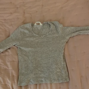 Ljusgrå långärmad tröja - Säljer en super gullig tröja med en liten rosett på framsidan på och även med spets på storlek är 146-152 alltså storlek XXS 