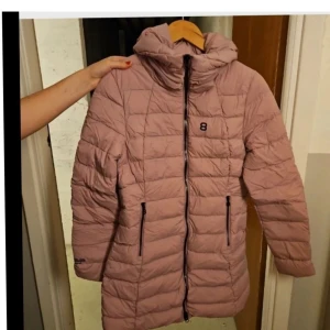 Arabella altitude nytt - OANVÄND snygg och varm dunkappa/parkas i en fin lila/ljungfärg. Jackan har en huva och en dragkedja framtill.  Nypris 2500 kr. Märke arabella altitude