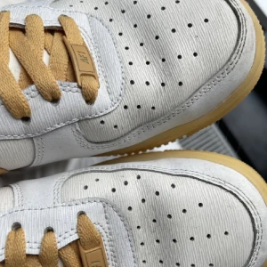 Nike Air Force med beige detaljer - Säljer ett par snygga Nike Air Force med en clean vit bas och coola beige detaljer. Skorna har klassisk snörning och en bekväm passform. Använda ca 4ggr. Säljes pga att de är fel storlek och tyvärr inte passar mig. Nypris 1500kr