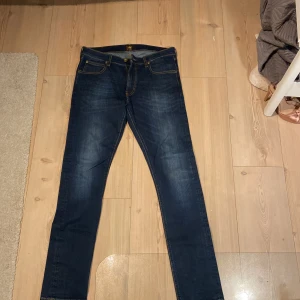Mörkblå jeans från Lee - Säljer ett par snygga mörkblå jeans från Lee. De har en klassisk femficksdesign och är i en slim passform. Perfekta för både vardag och fest! 🕺 Modell:LUKE Skick: nästan oanvända. Nypris 800:-