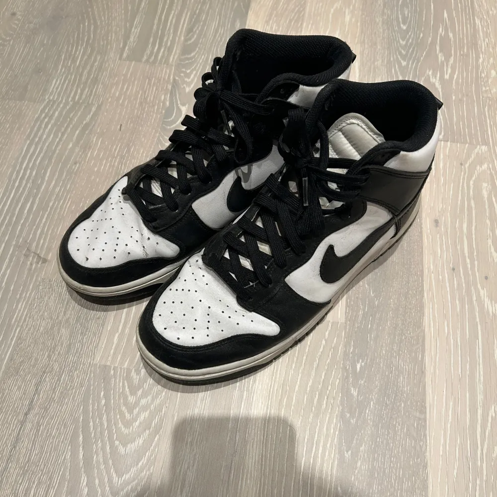 Säljer ett par snygga svartvita Nike Dunk sneakers. De har en klassisk design med svart snörning och en vit bas med svarta detaljer. Perfekta för både vardag och fest!. Skor.